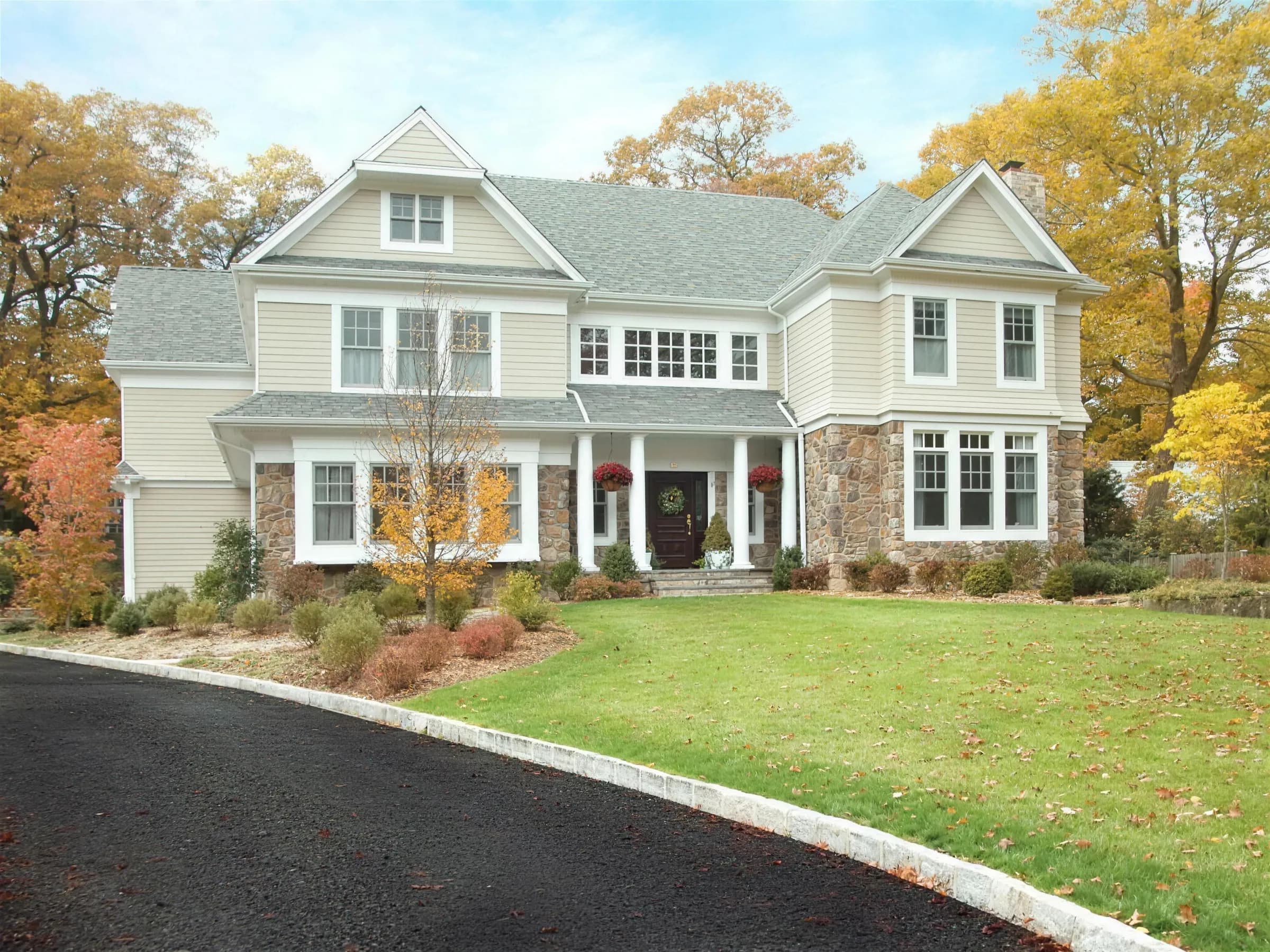 A New Jersey colonial with a stone-trimmed porch and autumn trees along a curved drive