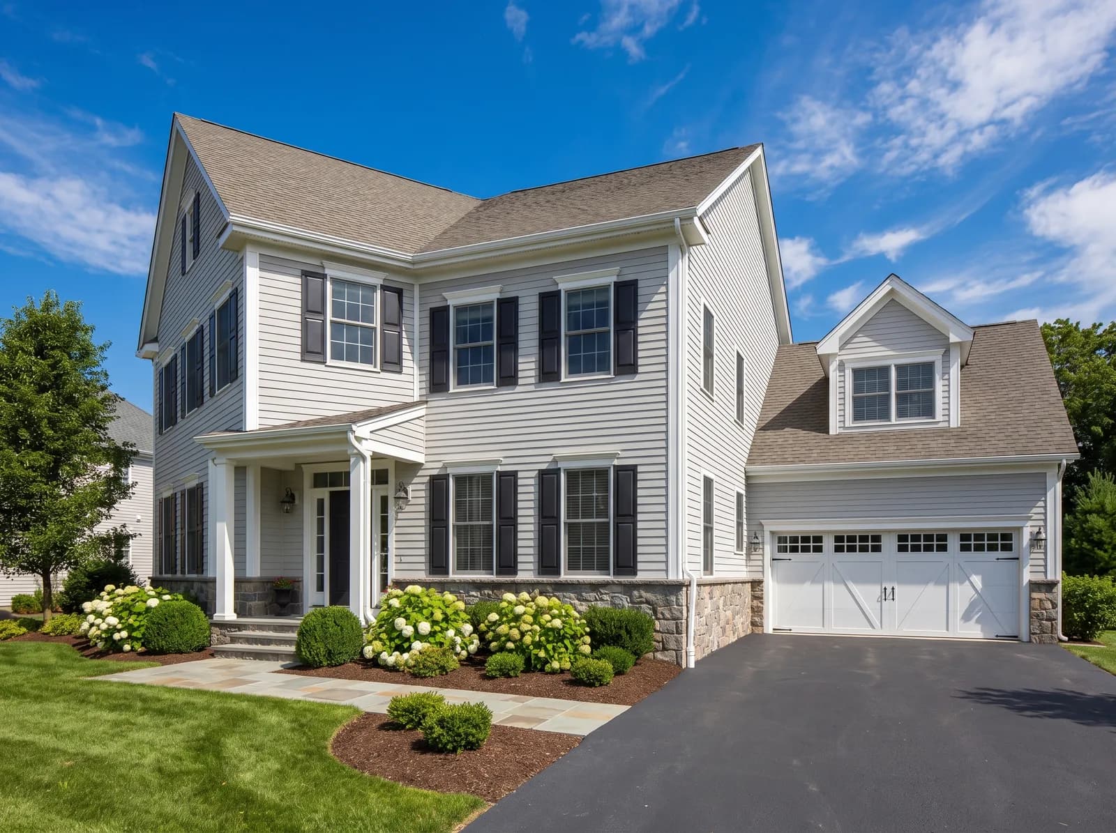 A well-kept two-story house photographed straight on, with clipped hedges and a bright sky
